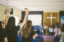 people with hands raised during a worship service 