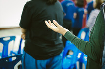 a person standing with hands raised at a worship service 