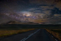stars in the night sky above a road 
