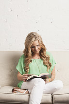 woman reading a Bible sitting on a white couch