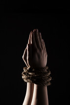 Wrists bound by rope.