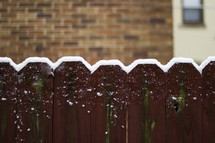 Snow on the top of a fence.