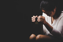Woman holding her bible and bowing her head in prayer