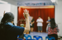 a woman standing with hands raised at a worship service 