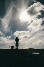 silhouette of a man standing under a cloudy sky 