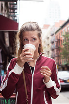 a woman drinking from a paper coffee cup 