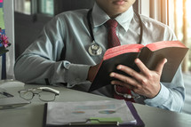 A doctor reading a Bible at his desk during a break