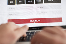 closeup of man donating to a charity or tithing to a church online and getting ready to click the give now button. 