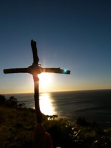 Silhouette of a cross with sunset on the water.