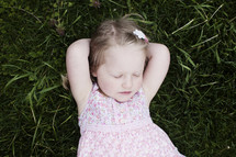 toddler girl lying in the grass with her eyes closed