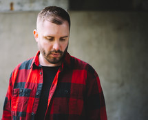 a man in a flannel shirt looking down 