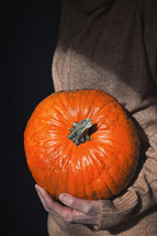 Woman holding bright orange pumpkin