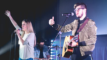 worship leaders singing into a microphone on stage 