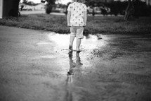 A toddler girl walking in a puddle of water 