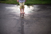 Child's feet standing in a puddle after the rain.