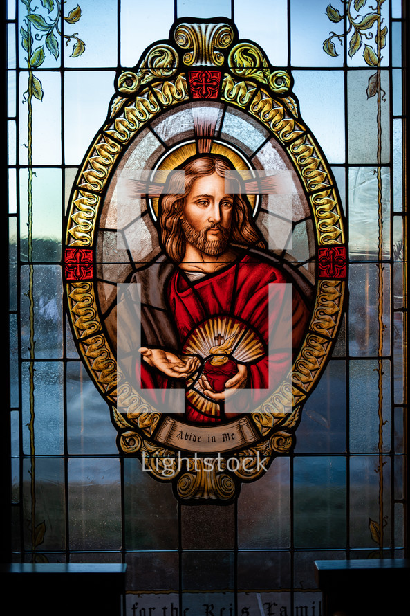 Stained glass window of Jesus alight with Compassion.