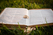 wedding rings on an open Bible in the grass