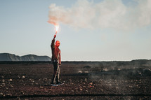 a man in a desert holding a flare 