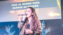 woman holding a microphone and singing during a worship service 