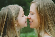 Smiling mother and daughter touching noses.
