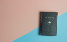 A Holy Bible on a pink and blue background 