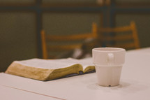 open Bible on a table and coffee mug 