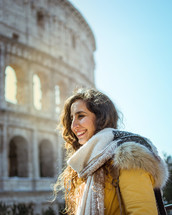 a woman in a coat standing by the Colosseum in Rome 