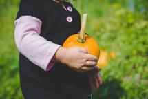 toddler girl carrying a pumpkin 