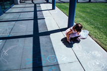 a child drawing with sidewalk chalk 
