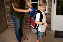 a mother helping her son get ready for school 