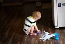 toddler boy cleaning up spilt milk 