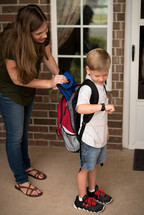 mother helping a child get ready for school 