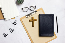 clipboard, Bible, and notebook on a desk 