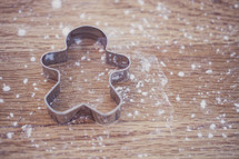 flour on a table and gingerbread man cookie cutter 