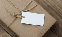 A white tag on a brown paper package tied with twine.