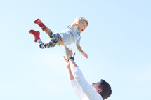 a man tossing her son in the air 