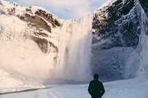 a man watching waterfall in snow 
