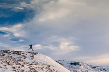 a man leaping on top of a mountain top 