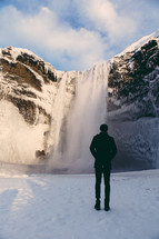 a man looking at a waterfall in snow 