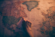 hand pointing to North America on a world map 