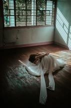 a dancer in a white dress on a wood floor 