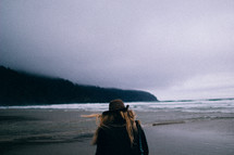a woman walking on a beach in a coat 