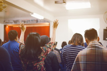people standing with hands raised at a worship service 