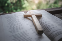 a wooden cross on the pages of a Bible 