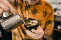 barista pouring creamer in a mug 