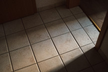 sunlight through a doorway shining onto a tile floor 