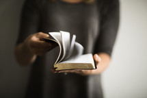 A woman opening a Bible and flipping through the pages. 