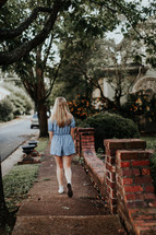 teen girl walking down a neighborhood sidewalk 