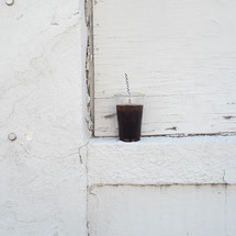 plastic cup of soda and straw on a ledge 