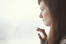 A teenage girl looking out a window 